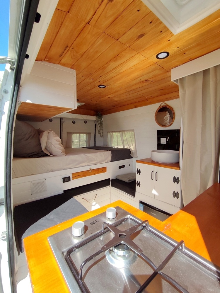 Image of a camper van interior showing customised cabinets, a stone sink and modern furnishings
